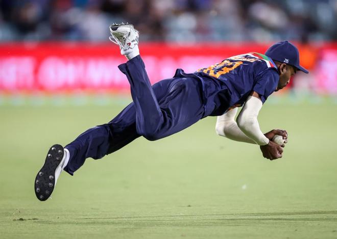 Hardik Pandya de la India se zambulle para atrapar al capitán de Australia, Aaron Finch, durante el partido de cricket T20 entre la India y Australia en el Manuka Oval de Canberra.