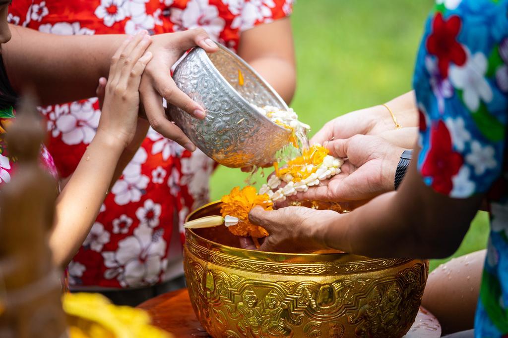 Familia virtiendo agua perfumada sobre las manos de sus mayores en señal de respeto