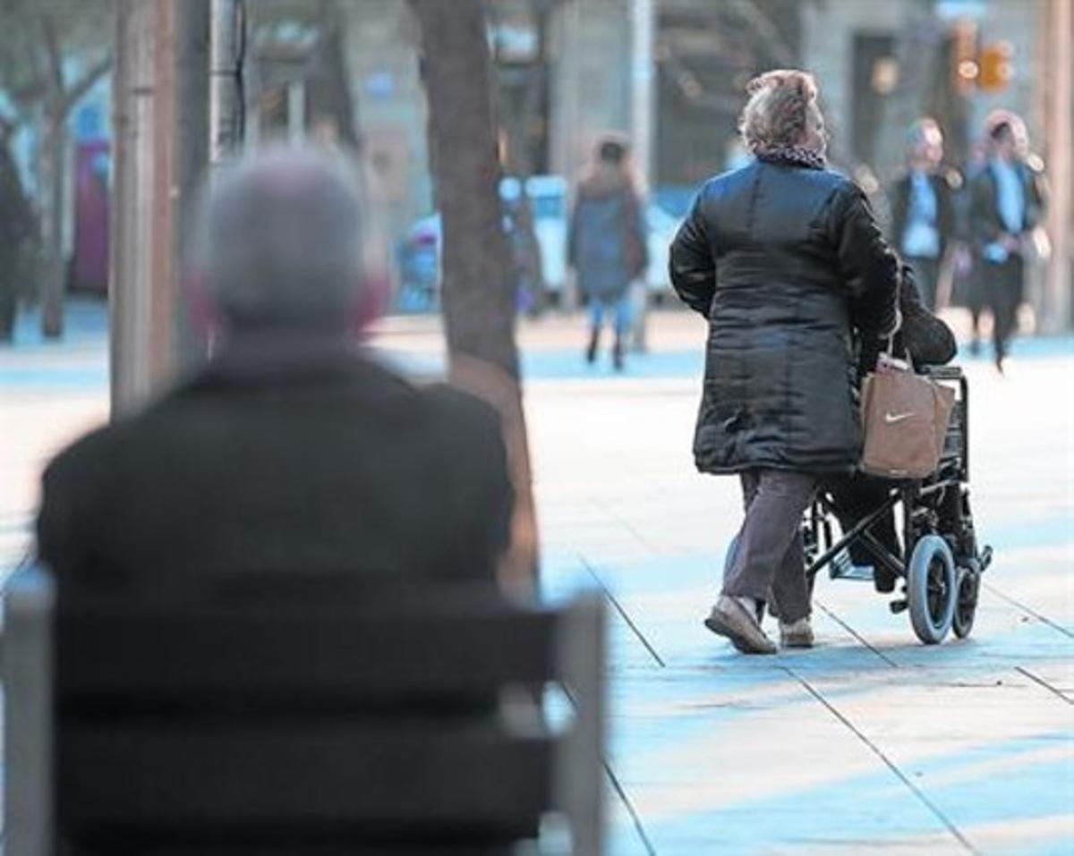 Una dona passeja al seu marit en cadira de rodes, a Barcelona.