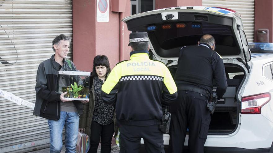 Inquilins sortint del bloc amb una peixera del seu pis.