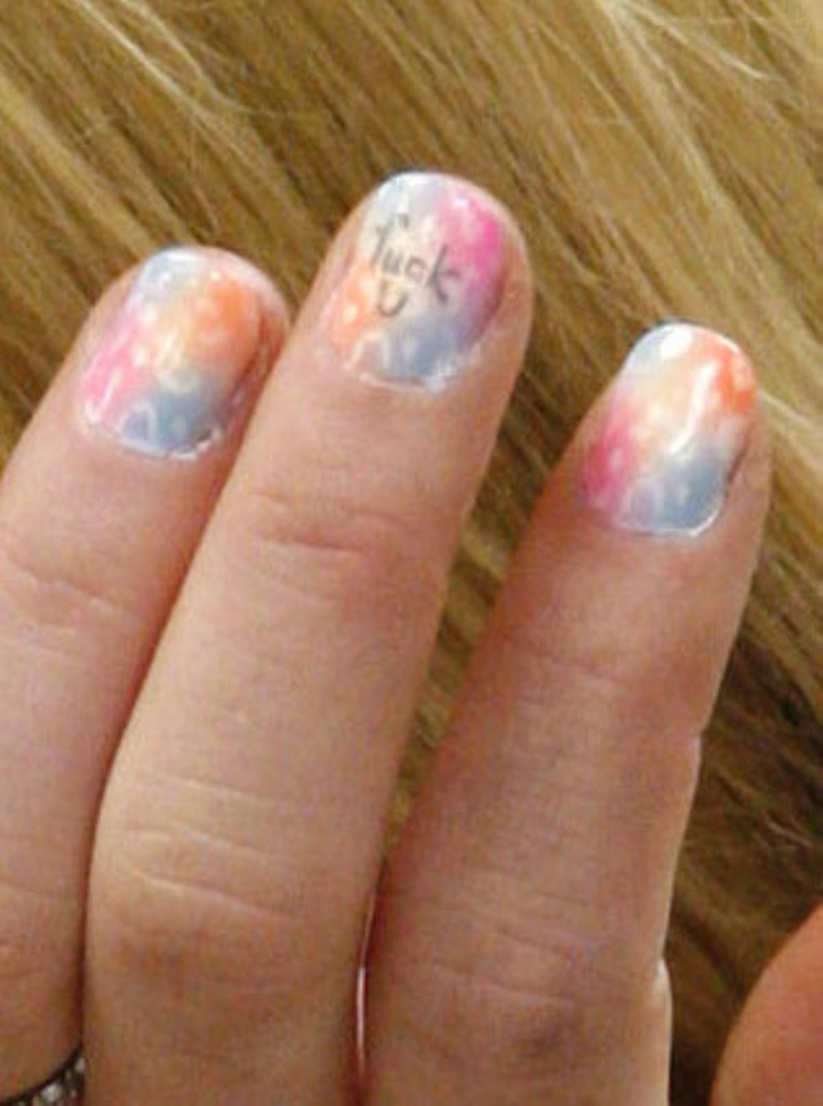 Detalle de la mano izquierda de Lohan durante la celebración del juicio. Pintado en la uña del dedo corazón puede leerse el lema: Que te den.