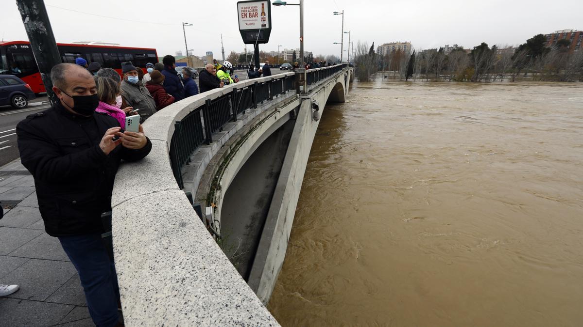 Los curiosos fotografían el río en el puente de Santiago.