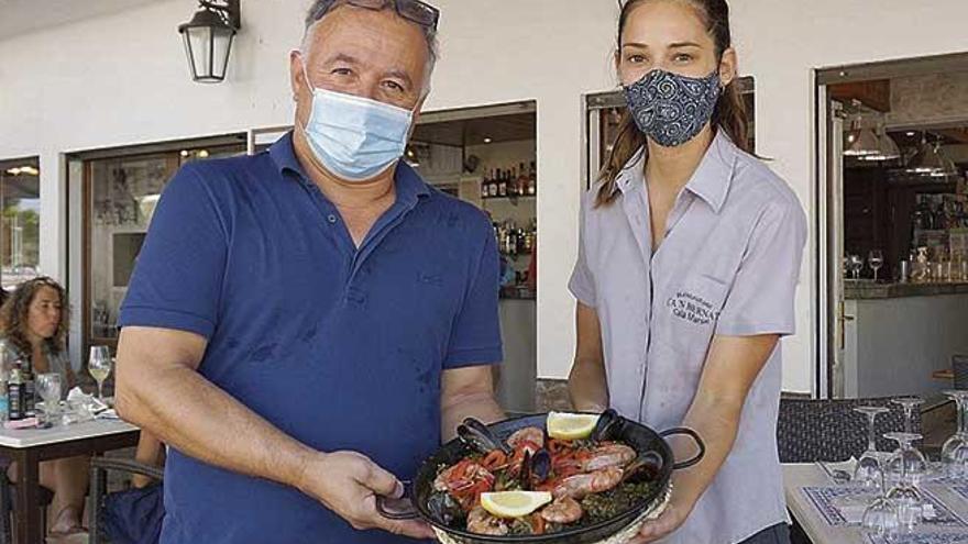 Miquel Ramis, propietario, y Xisca Pascual, camarera, con una paella mixta para dos personas.