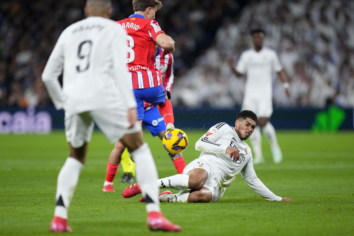 Real Madrids Jude Bellingham, on the ground, vies for the ball with Atletico Madrids Pablo Barrios during a Spanish La Liga soccer match between Real Madrid and Atletico Madrid at the Santiago Bernabeu stadium in Madrid, Saturday, Feb. 8, 2025. (AP Photo/Manu Fernandez). EDITORIAL USE ONLY/ONLY ITALY AND SPAIN