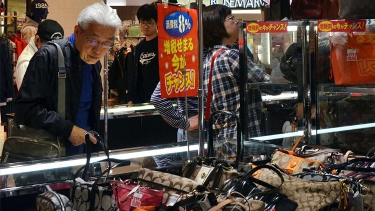 Un ciudadano japonés mira bolsos en una tienda en Tokio.