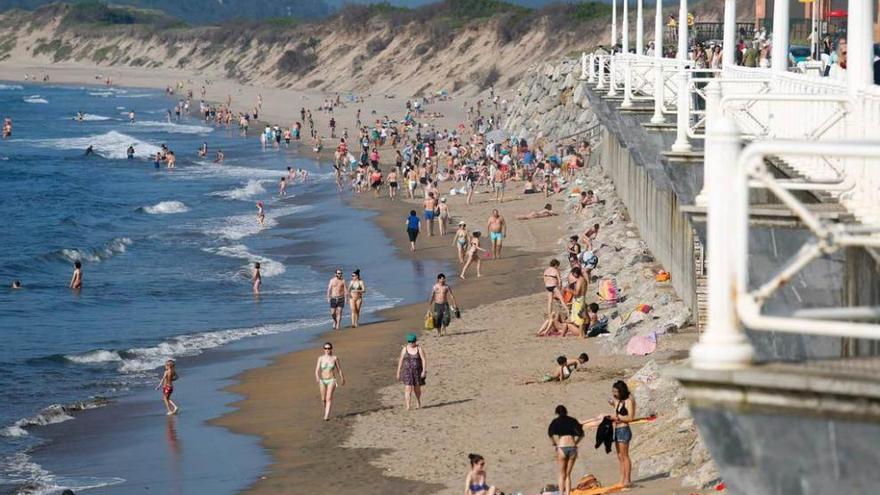 Bañistas, algunos en la escollera sin arena, en la playa de Salinas, ayer por la tarde, en pleamar.