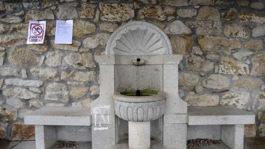 Junto a la fuente se colocó un cartel con el resultado de las analíticas y otro con la leyenda de &quot;agua no potable&quot;. // Bernabé/Javier Lalín