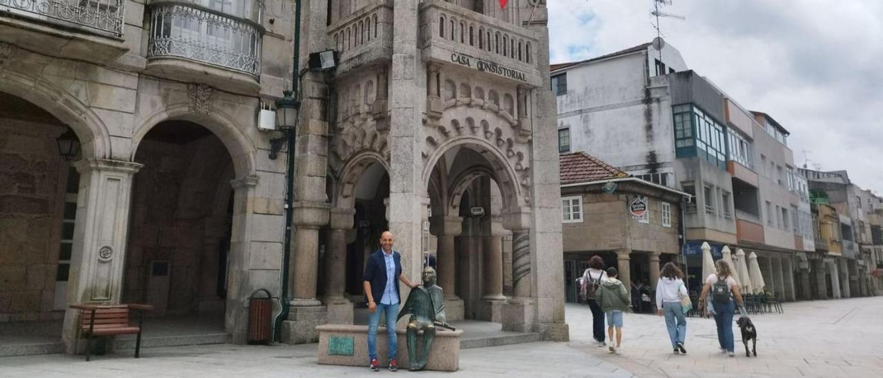 Alejandro Lorenzo junto a la estatua de Antonio Palacios en la plaza que lleva su nombre, y detrás el Concello, obra también del arquitecto, hijo predilecto de la villa.  // D. P.