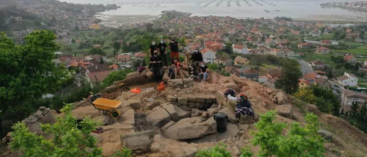 Benito Vilas (en primer término, mascarilla negra), con Paula Méndez, Nerea Vilariño, Elena Taboada y colaboradores, en el yacimiento de A Torre, con Moaña al fondo.