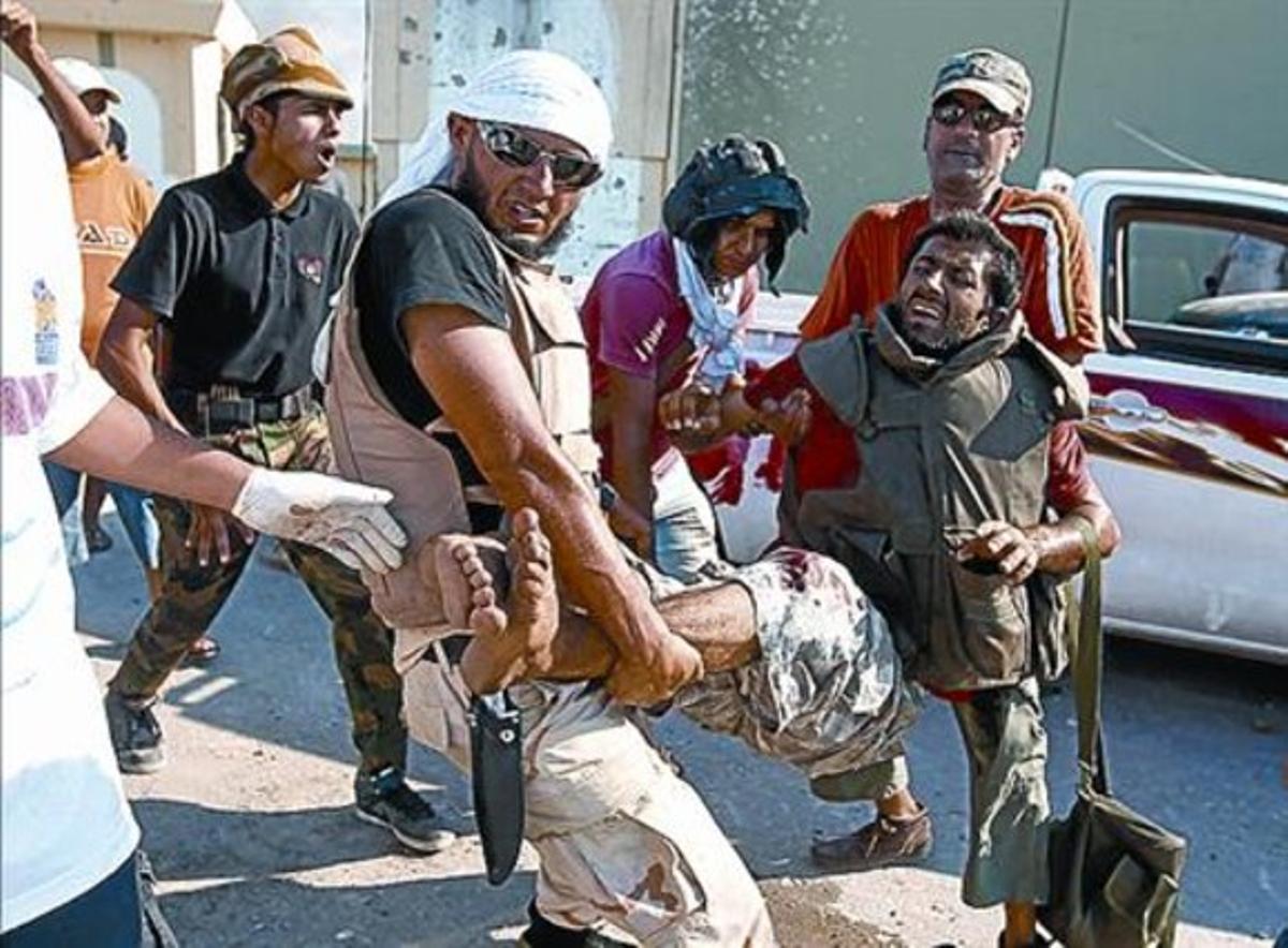 EUFÒRIA I DOLOR 3 Un noi enarbora la bandera tricolor a Bengasi (esquerra). Un grup rebel ajuda un company ferit a les portes de la residència de Gaddafi (a dalt). A sota, destrosses al palau. EUFÒRIA I DOLOR 3 Un noi enarbora la bandera tricolor a Bengasi (esquerra). Un grup rebel ajuda un company ferit a les portes de la residència de Gaddafi (a dalt). A sota, destrosses al palau.
