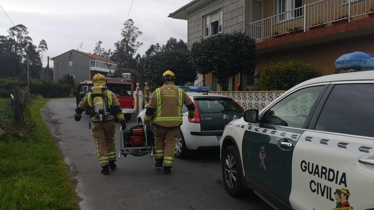 Efectivos de emergencias llevando un ventilador para desalojar el humo de la vivienda.