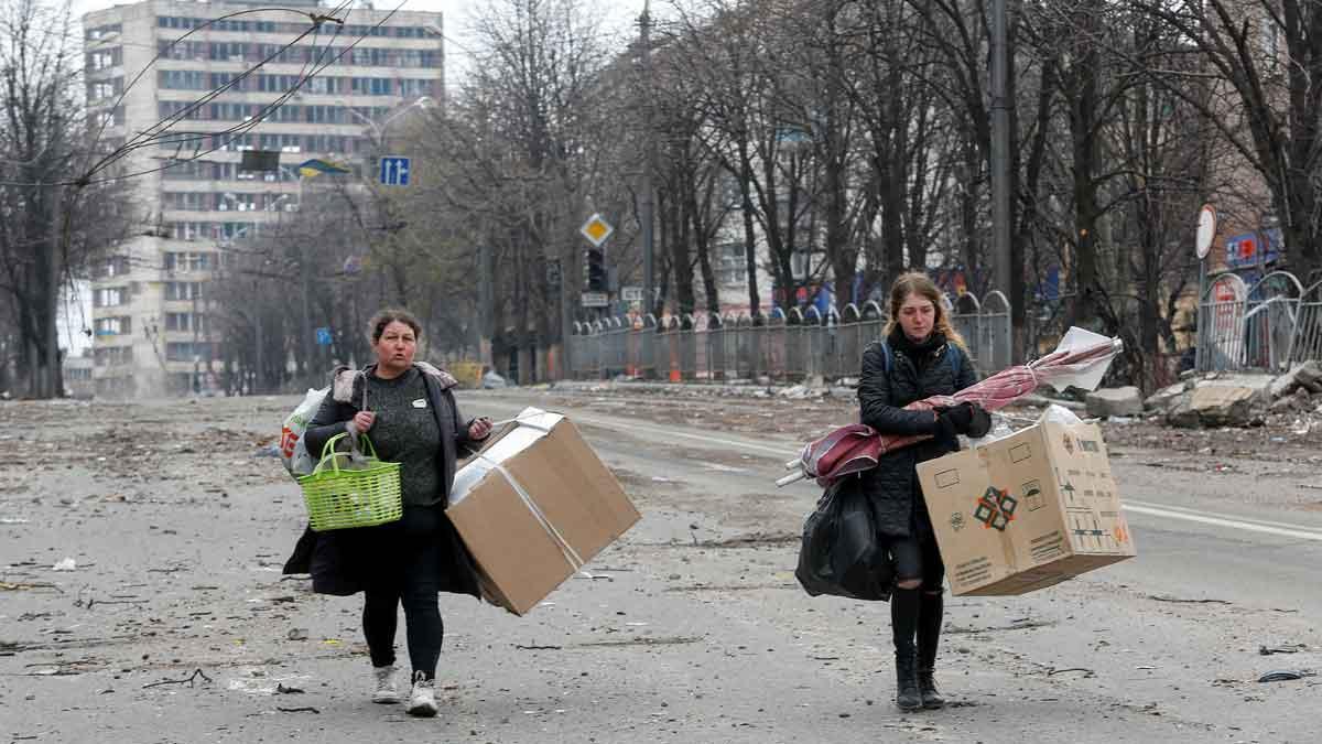 Dos mujeres trasladan sus pertenencias, en una calle de la ciudad ucraniana de Mariúpol