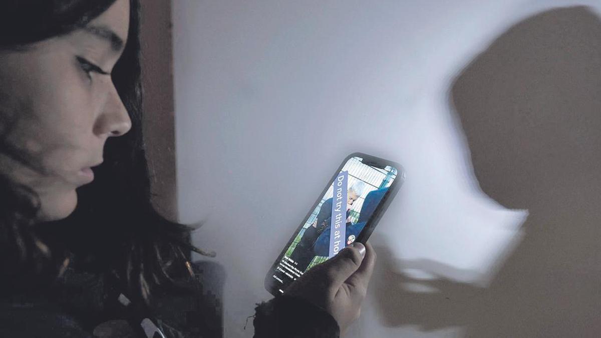 Una adolescent mira un vídeo de TikTok en el seu mòbil