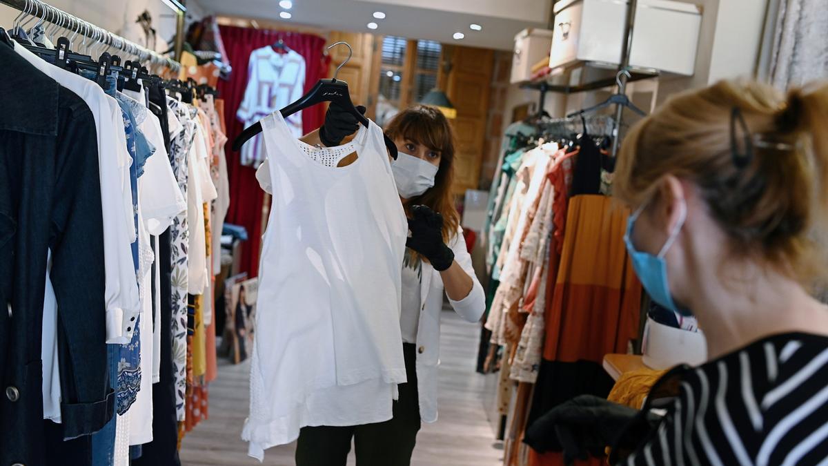 Una trabajadora desinfecta una prenda en una tienda de ropa en Madrid
