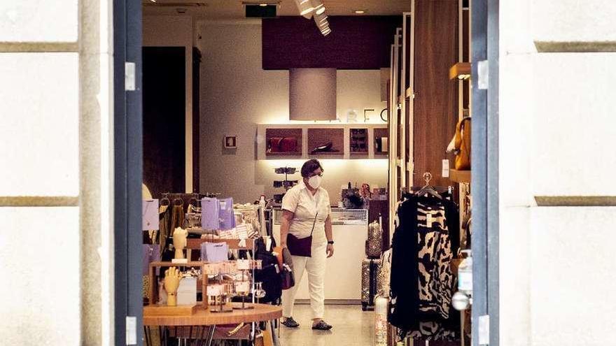 Una mujer observa prendas en el interior de una tienda en la calle del Paseo. // Carlos Peteiro