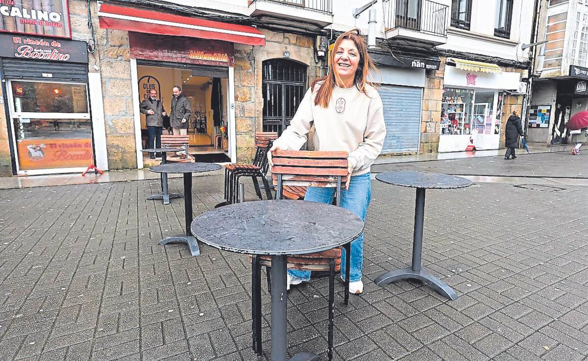 Fini Acuña, de El Club del Café, coloca una silla ante su local.