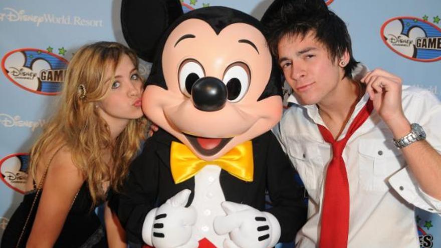 Andrea Guasch y Andreas Muñoz , de Disney España, posan junto al personaje Mickey Mouse en la alfombra roja previa a la Fiesta de las Estrellas del Canal Disney en la que se da apertura a los juegos de ese canal en el parque de atracciones Epcot en Lake Buena Vista, Florida (EEUU).