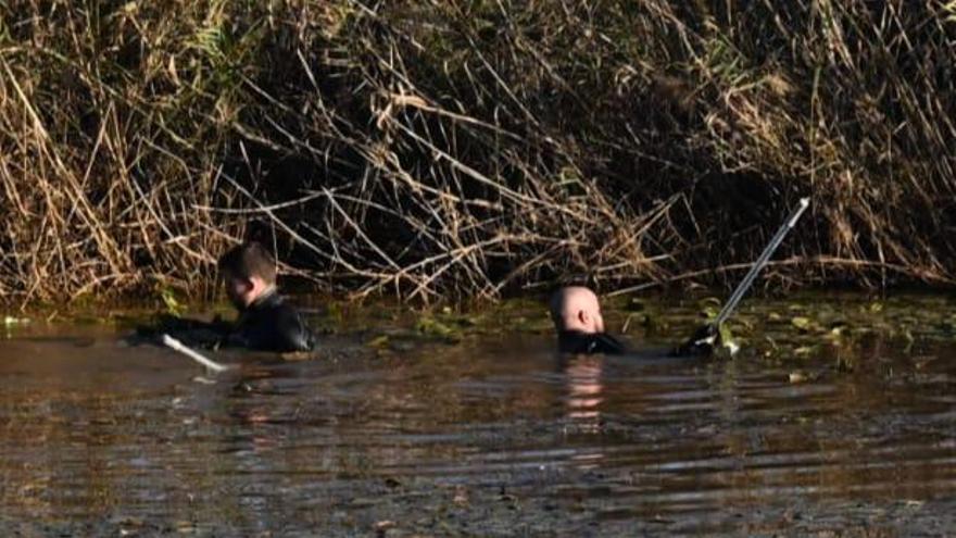 Los buzos rastrean la vegetación de la orilla desde dentro del agua.