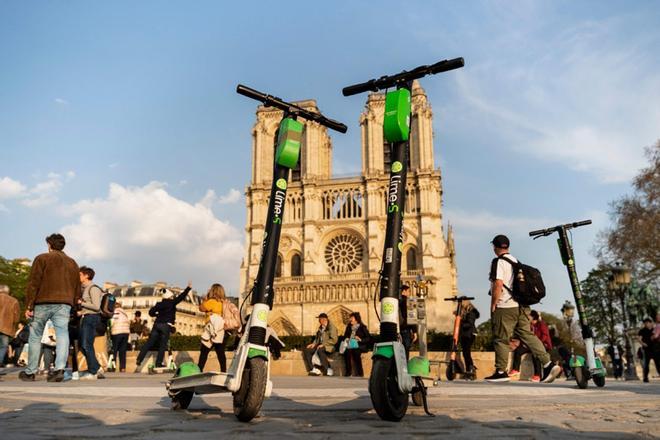 En esta foto de archivo tomada el 1 de abril de 2019, los scooters eléctricos de Lime-S de la compañía de transporte estadounidense Lime se muestran frente a la catedral de Notre-Dame de Paris en París.