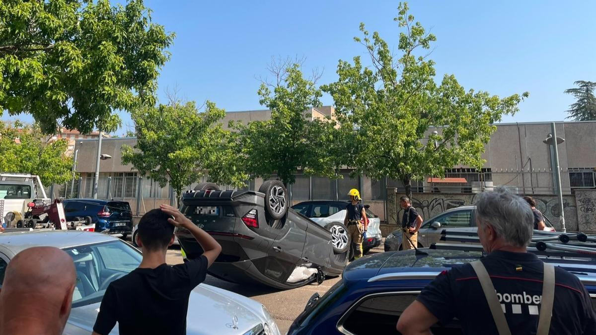 El vehicle bolcat i els Bombers fent les tasques de retirada al carrer Pau Masó