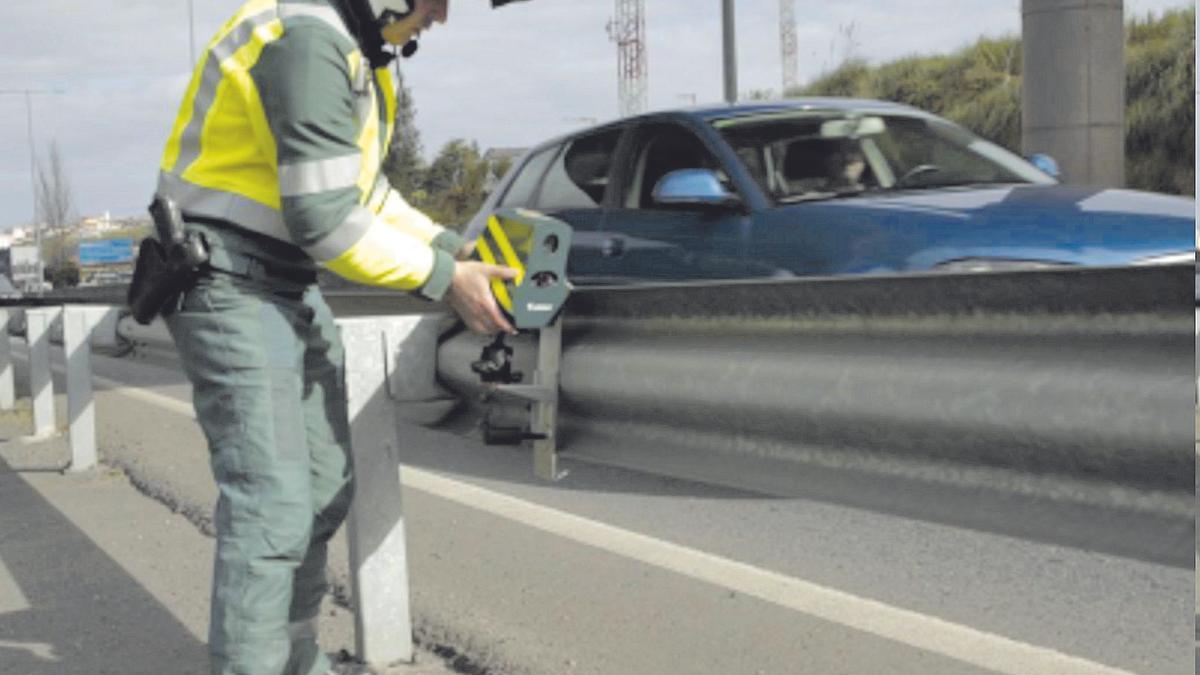 Un agente de la Guardia Civil coloca un radar móvil en una carretera convencional