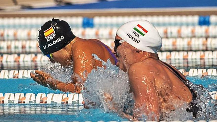 Alonso (i) y Hosszú, durante el calentamiento de los 50 braza; a la derecha, ambas nadadoras durante la prueba corta. | | ANDRÉS GUTIÉRREZ