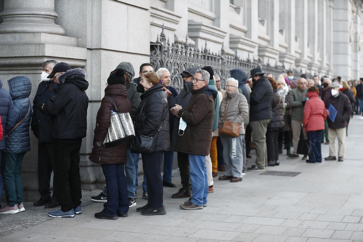 Numerosas personas hacen cola ante el Banco de España para comprar deuda pública.