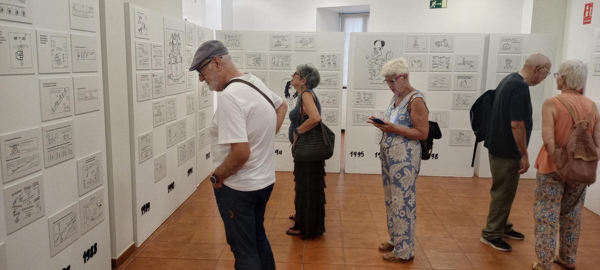 Algunos asistentes a la inauguración observan las viñetas que se exponen en la Casa de la Enseñanza.