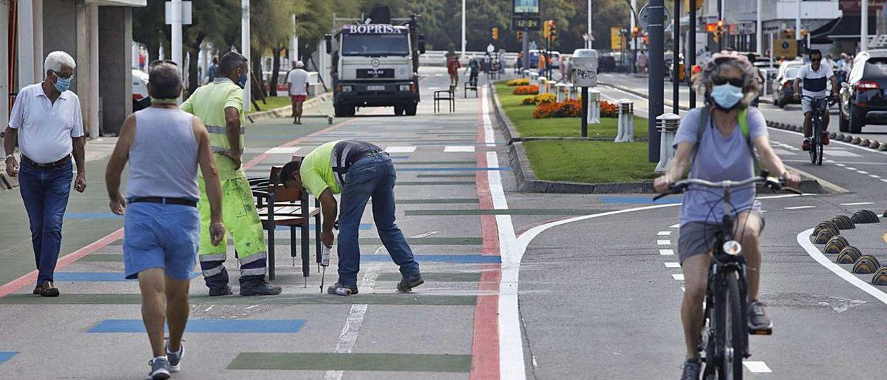 Operarios instalando ayer más bancos en la nueva zona peatonal del Muro.