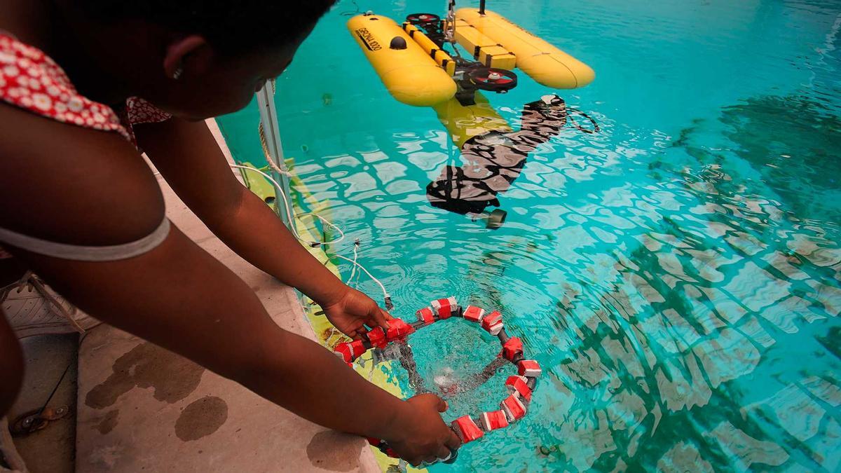 Una jove introduint el robot a la piscina del Parc Científic