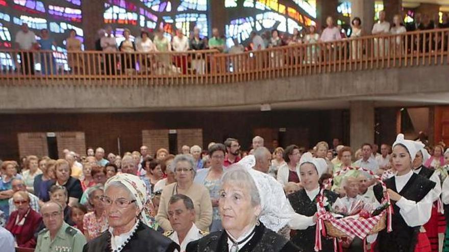 Integrantes del grupo «Xiringüelu» acercan hasta el altar la bandera de Gijón y la cesta con las ofrendas a la Virgen.