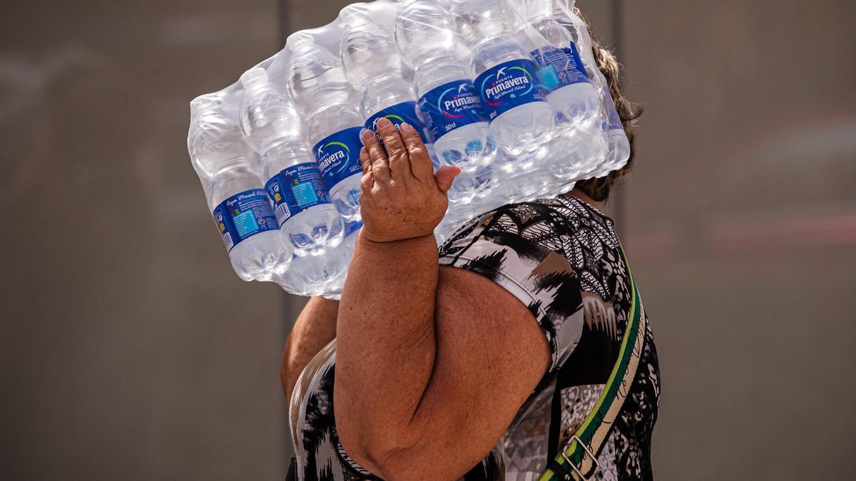 Una mujer lleva botellas de agua en la playa de la Malagueta este miércoles