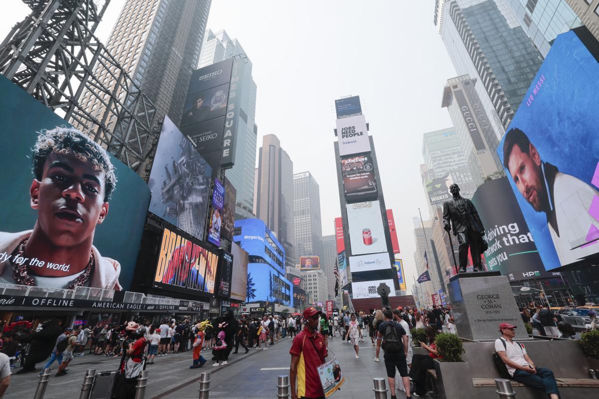 Personas caminan frente a carteles luminosos con la imagen de Lamine Yamal (i) de España y de Lionel Messi de Argentina, en Times Square en Nueva York (EEUU).