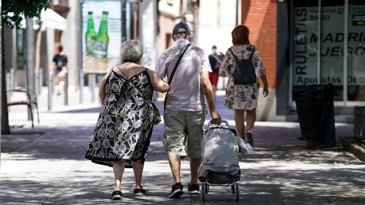 Dos personas mayores regresan a casa tras una compra.