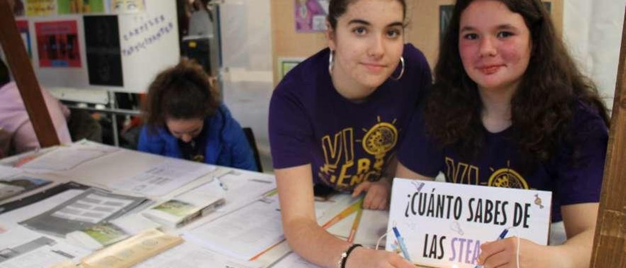 Aitana Cartategui y Rosa Rodríguez, en el stand donde informan sobre mujeres con trayectorias destacadas. A la izquierda, Marcos Fernández accede a través de un código QR a la información sobre Hipatia.