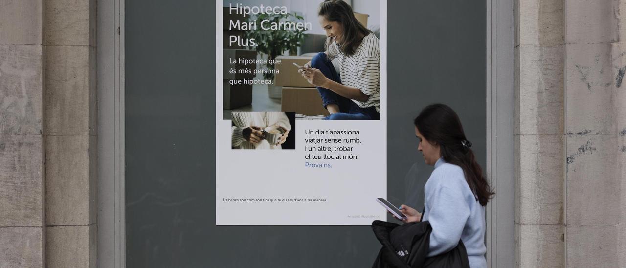Una dona camina davant d’un cartell publicitari sobre hipoteques, en una imatge d’arxiu.