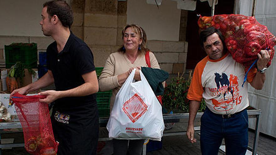 Tres personas hacen acopio de pimientos en uno de los puestos de la feria.