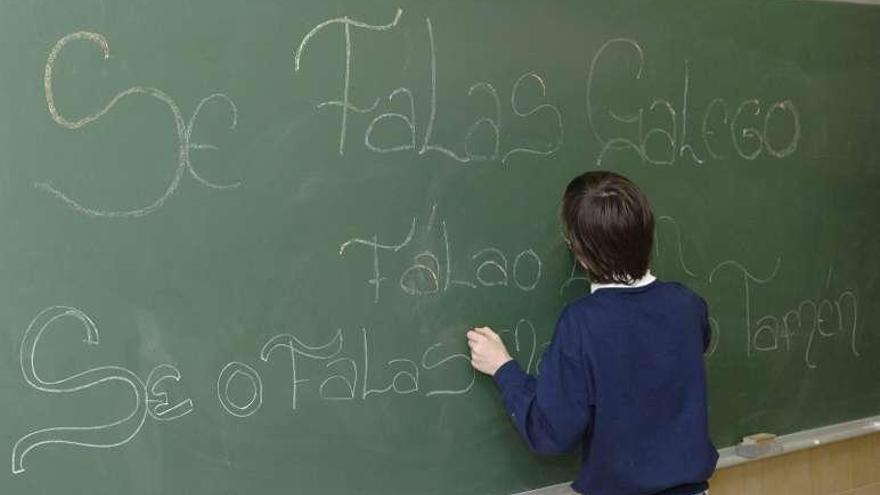 Un niño escribe en gallego en la pizarra de su clase.