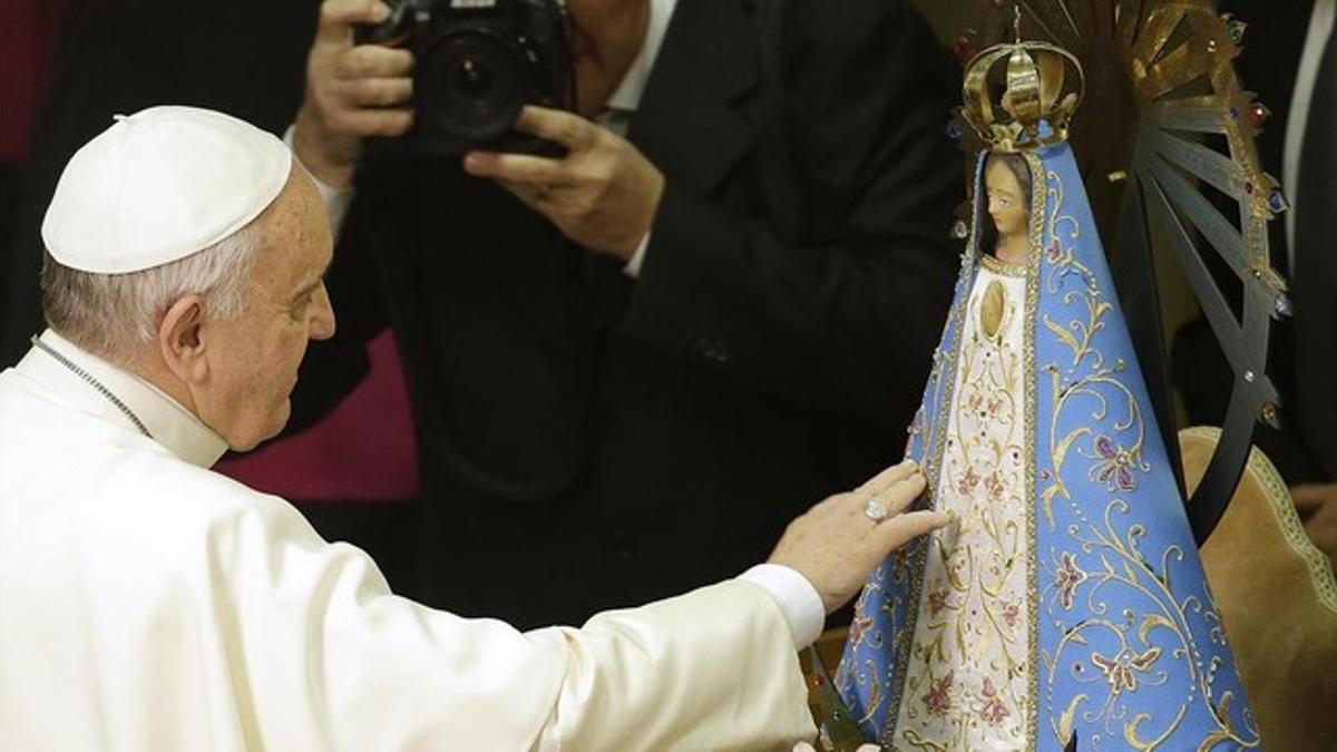 El Papa Francisco toca una estatua de la Virgen María durante una ceremonia en el Vaticano este jueves.