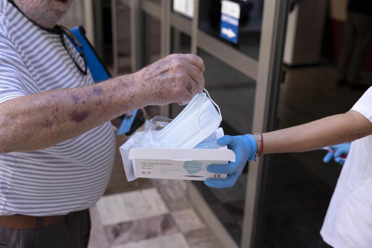Un hombre recoge una mascarilla a la puerta de su centro de salud en una fotografía de archivo.