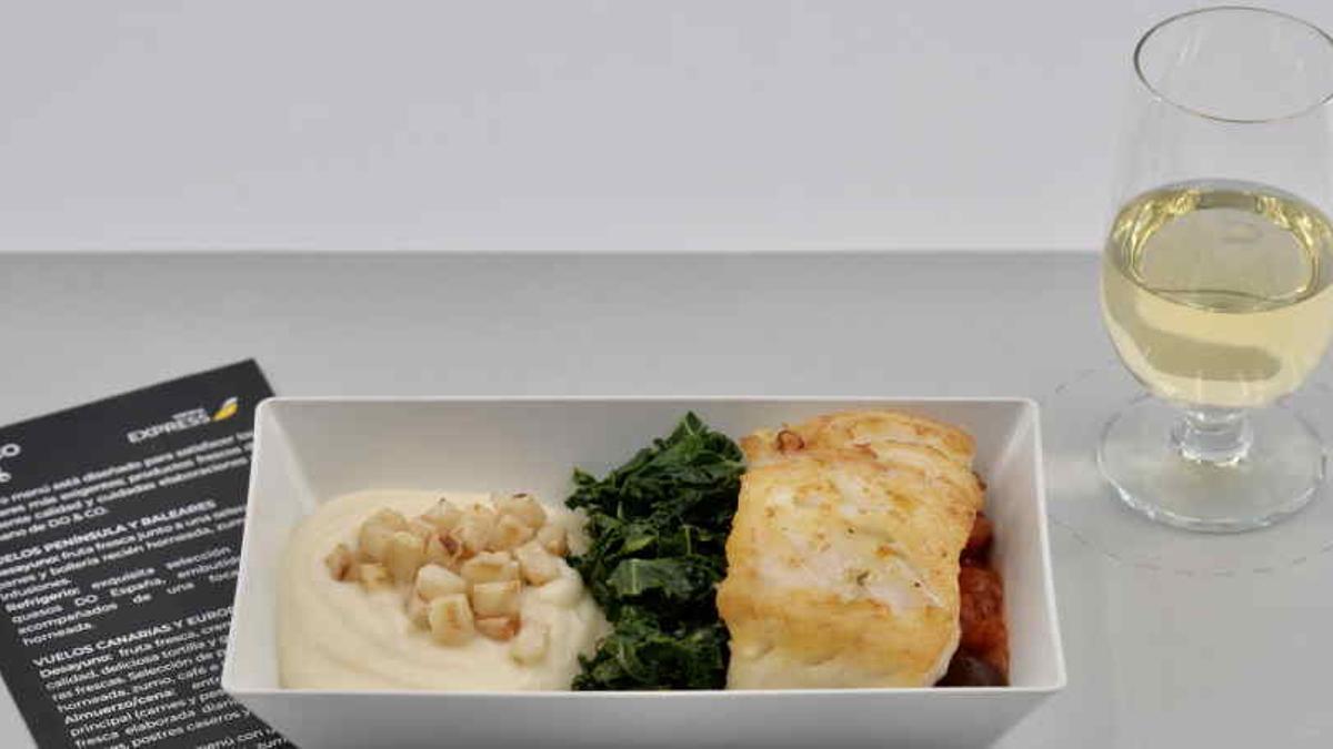 Una merluza al horno acompañada de un vaso de vino blanco