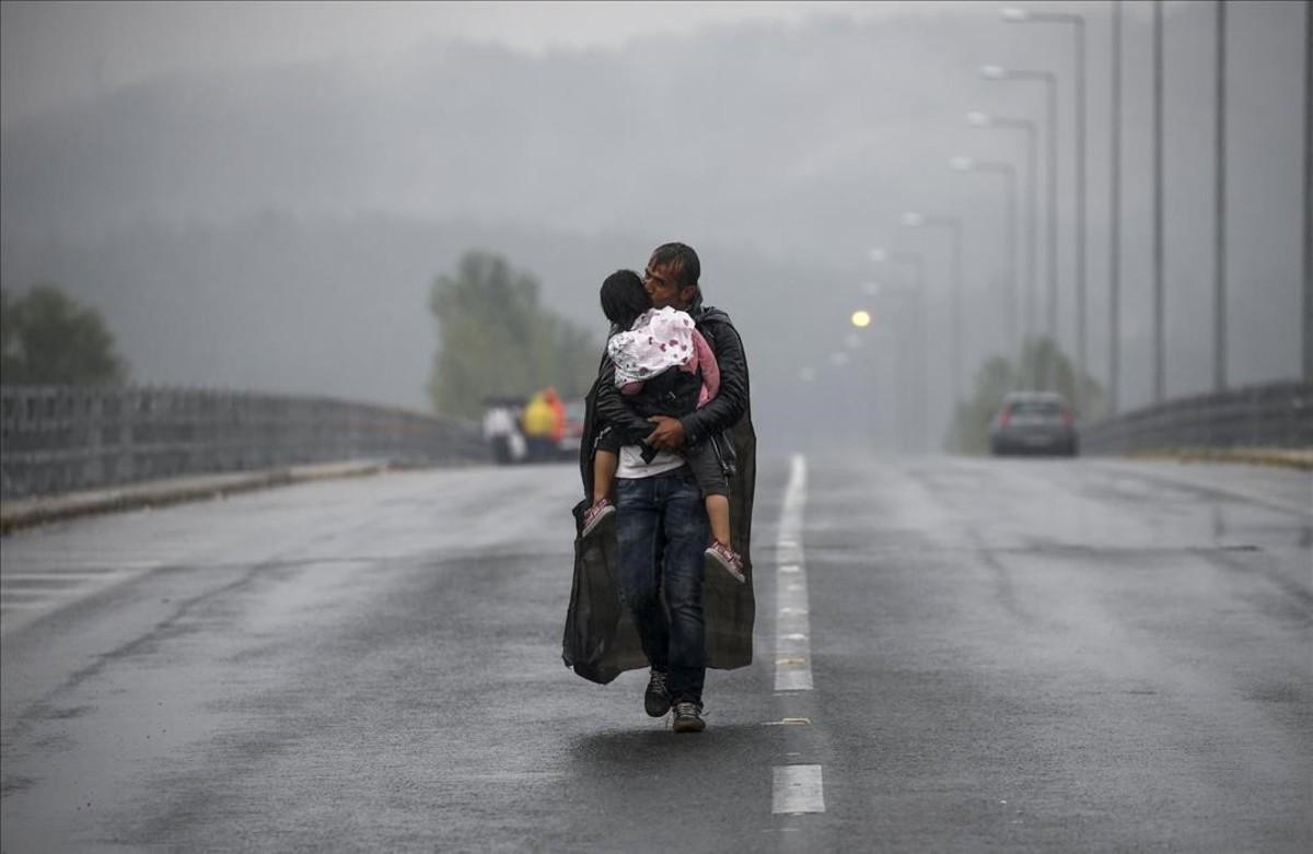 lpedragosa33590530 syrian refugee kisses his daughter as he walks thr160419172105