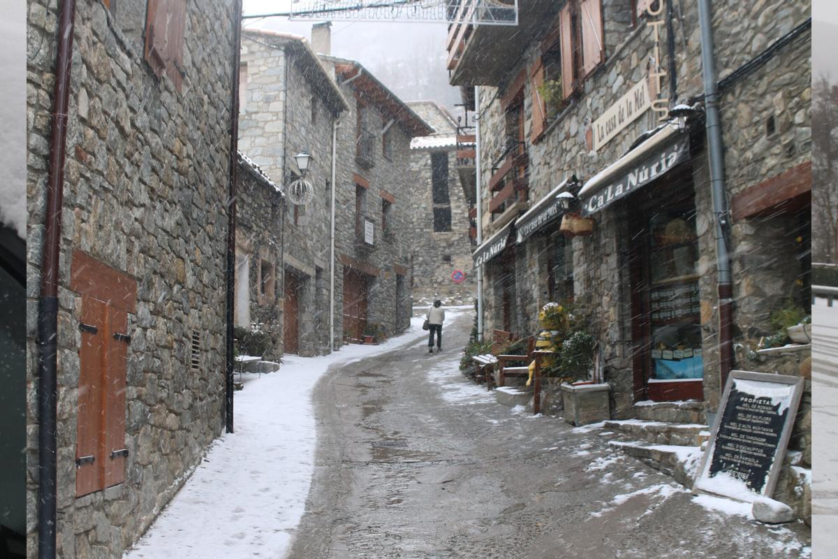 Una persona pujant pel nucli urbà amb el carrer nevat.