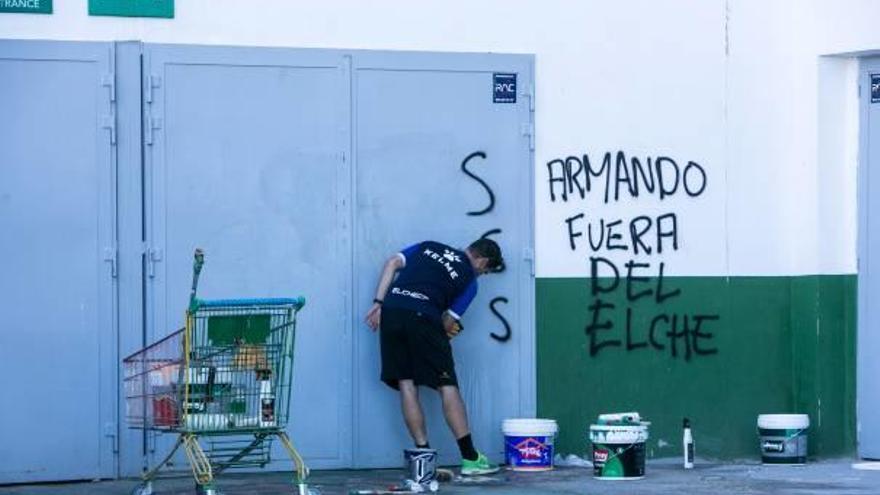 Un empleado del club borra las pintadas aparecidas en la noche del domingo en el Martínez Valero.