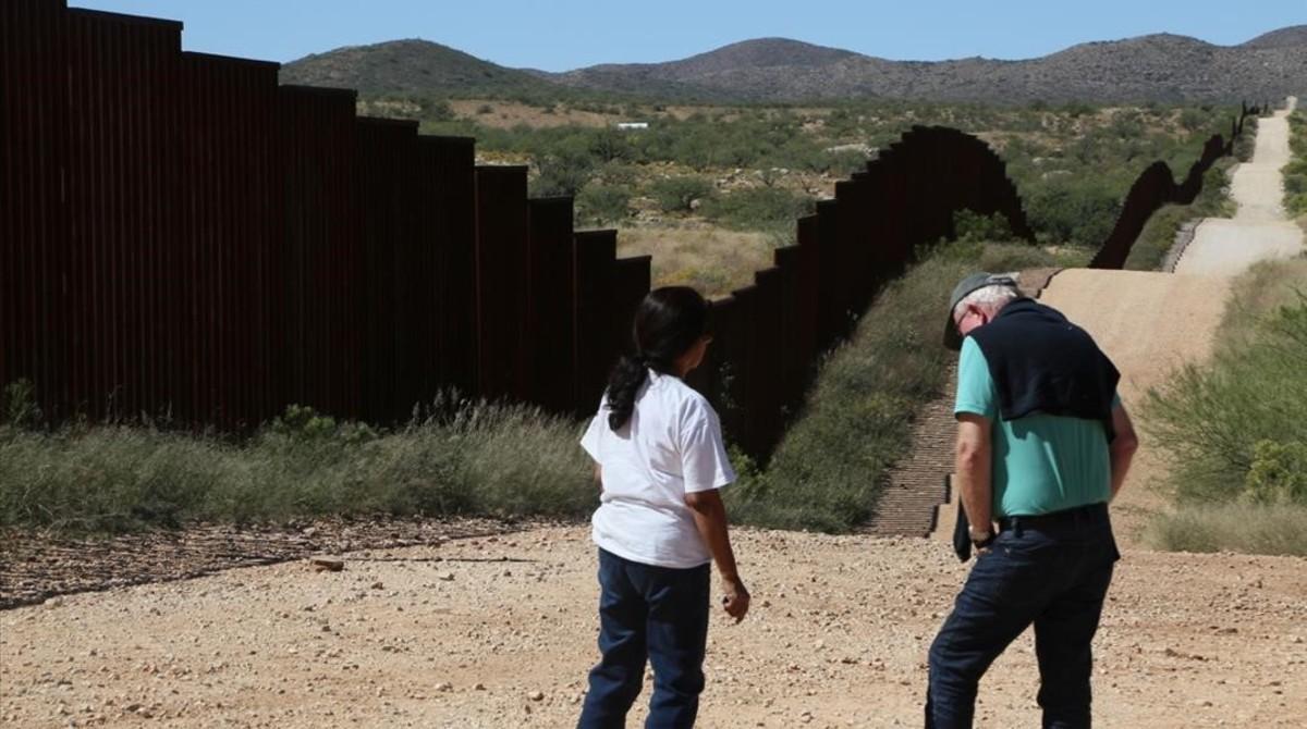 Dos personas junto a la valla fronteriza de Nogales.
