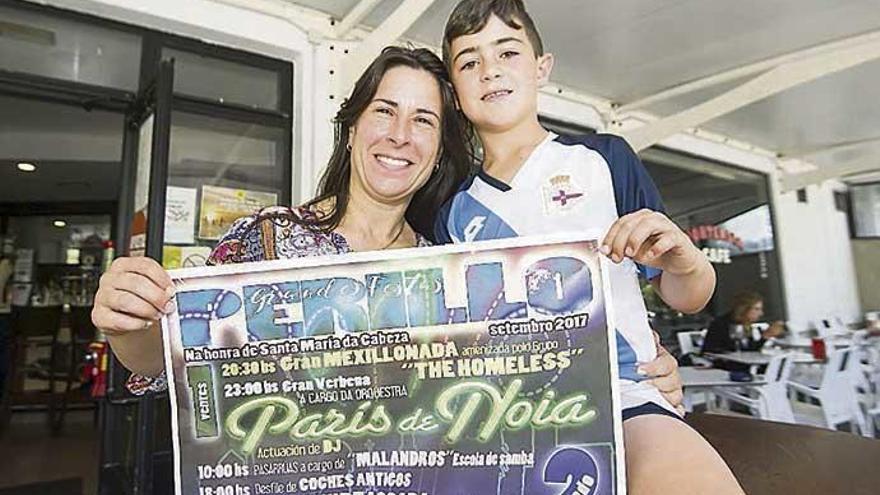 Raquel Armesto, en el café bar Hortensia de Santa Cristina con su hijo y el cartel de las fiestas.