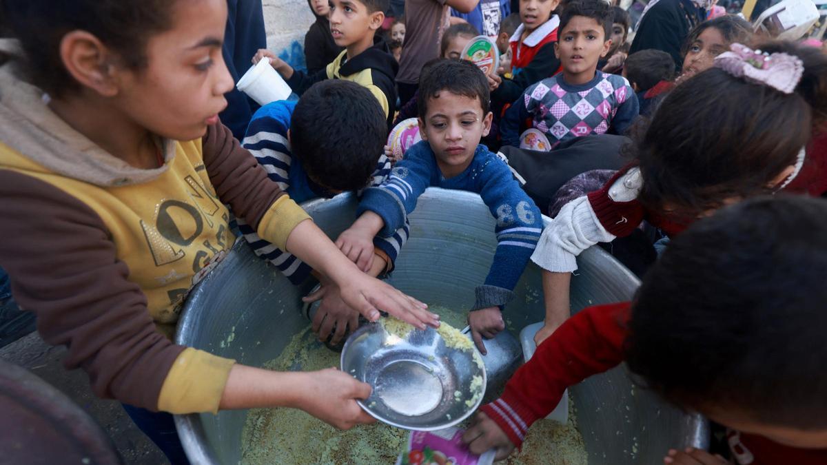 Un grupo de niños cogen comida de un punto de donación en la ciudad de Rafah, al sur de la Franja de Gaza.