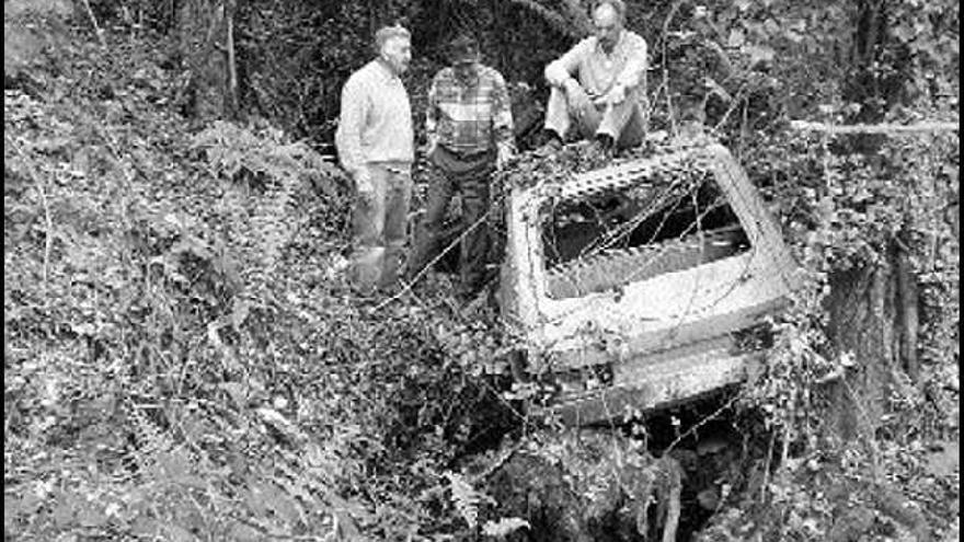 Miembros de la asociación de vecinos de Chapela muestran un coche abandonado en el cauce del río Maceiras. / A.M.