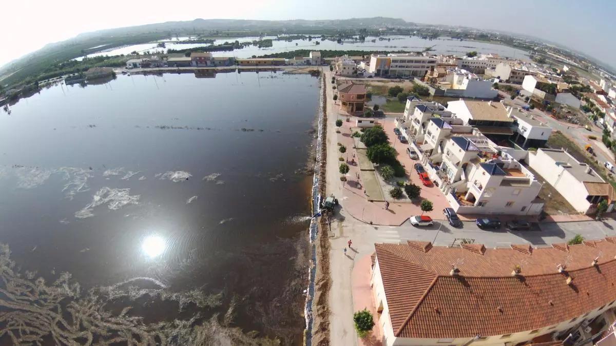 Los vecinos y el Ayuntamiento de San Fulgencio improvisaron una mota de tierra en las inundaciones de septiembre de 2019 que evitó que se anegara el casco urbano. En la imagen aérea se aprecia la mota junto al víal y los bancales anegados