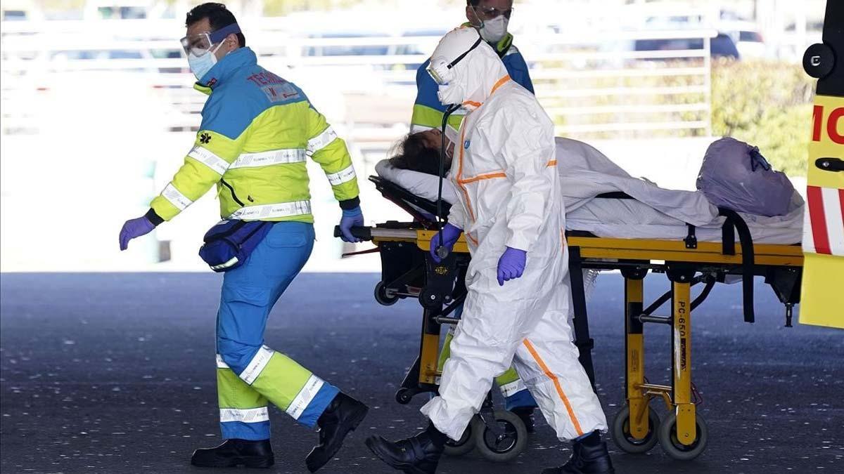 España vuelve a superar los 900 muertos por coronavirus en un día y ya se rozan los 11.000. En la foto, enfermeros trasladan a una mujer mayor con coronavirus a Urgencias del Hospital Puerta de Hierro en Majadahonda, Madrid.